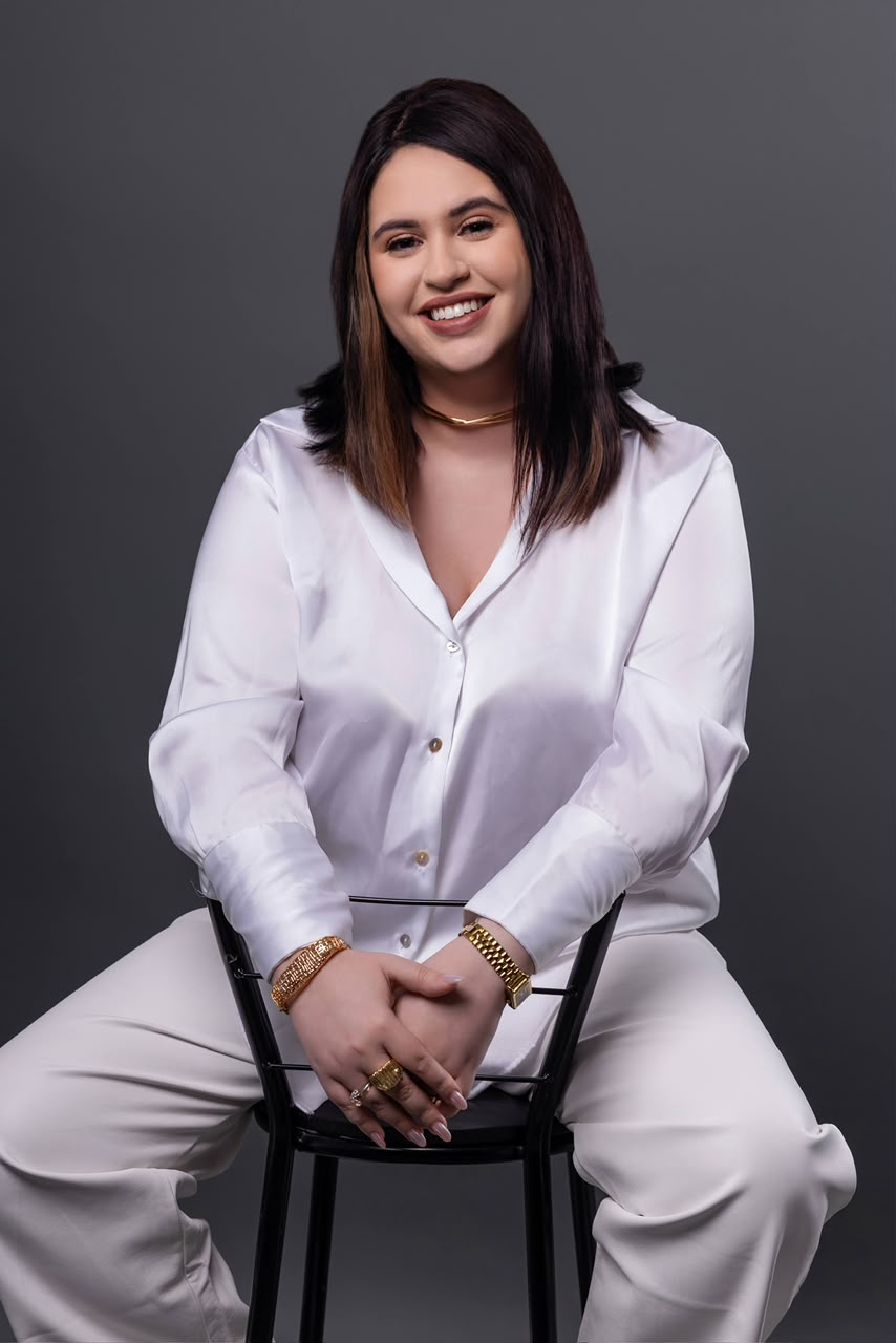 Dra. Isabela Bueno sentada, de branco, sorrindo